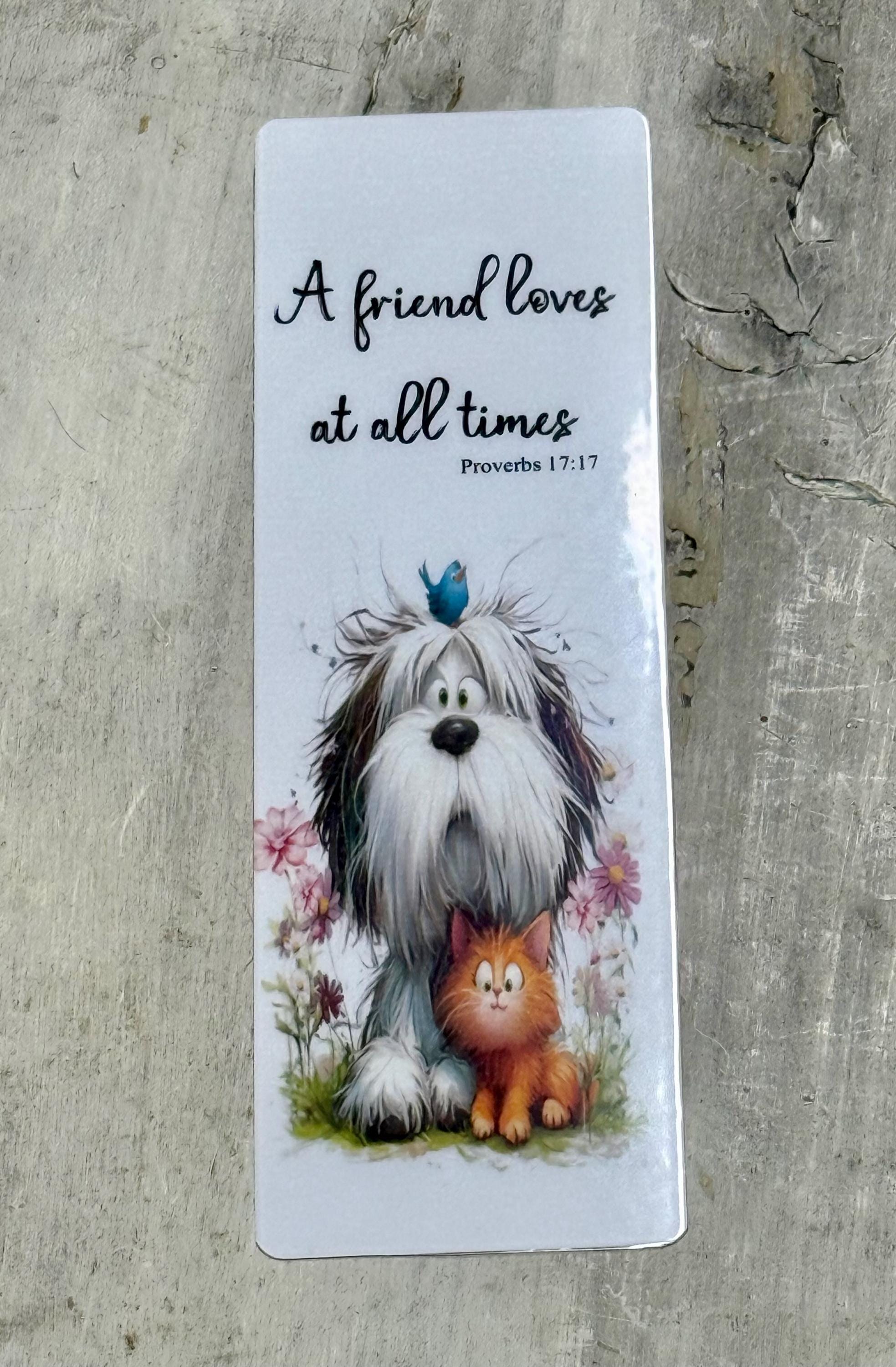 A white rectangular bookmark with a dog and a cat sitting together in a grassy area, surrounded by flowers.