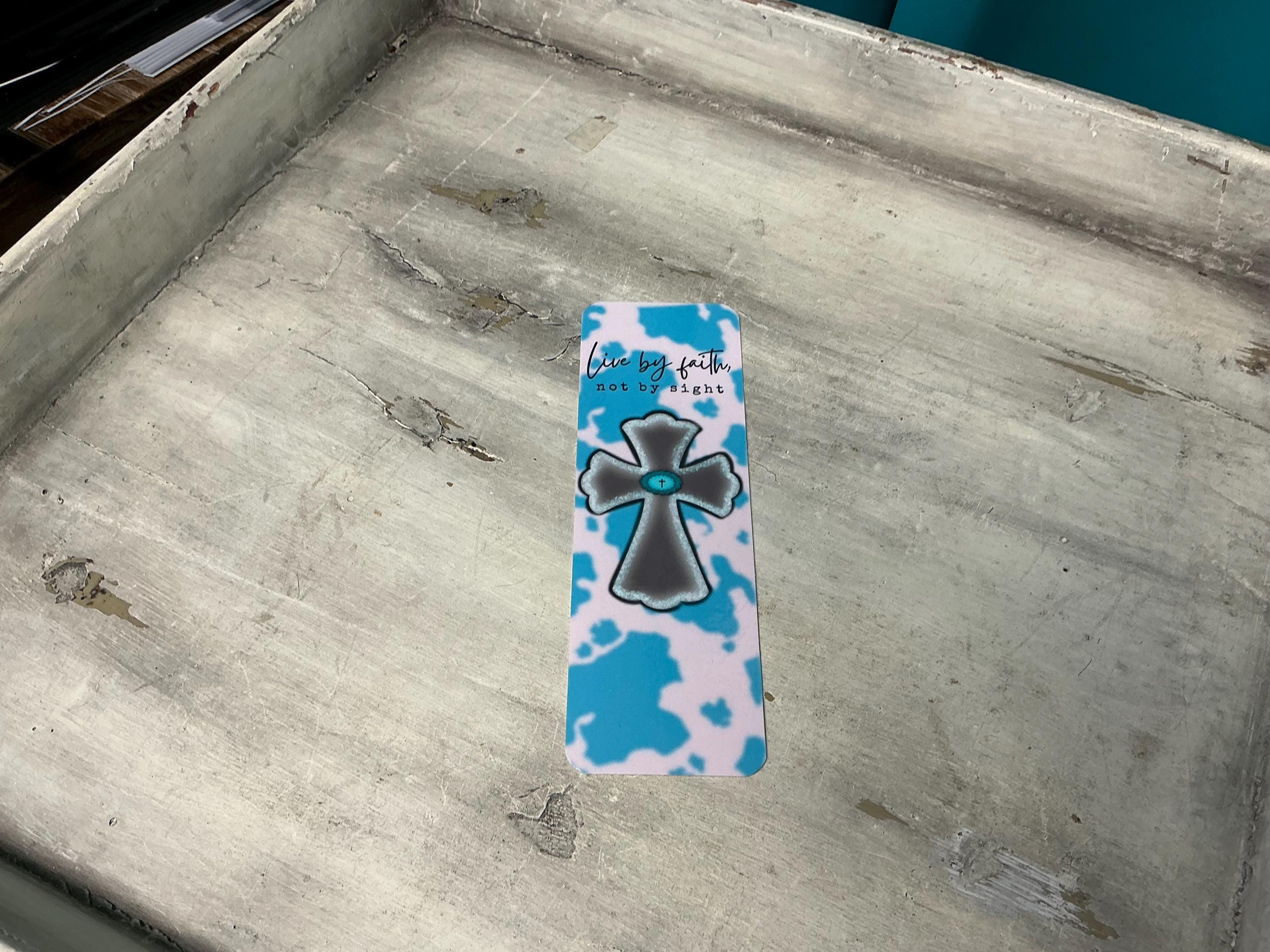 A blue and white cross-shaped bookmark is placed on a wooden surface.