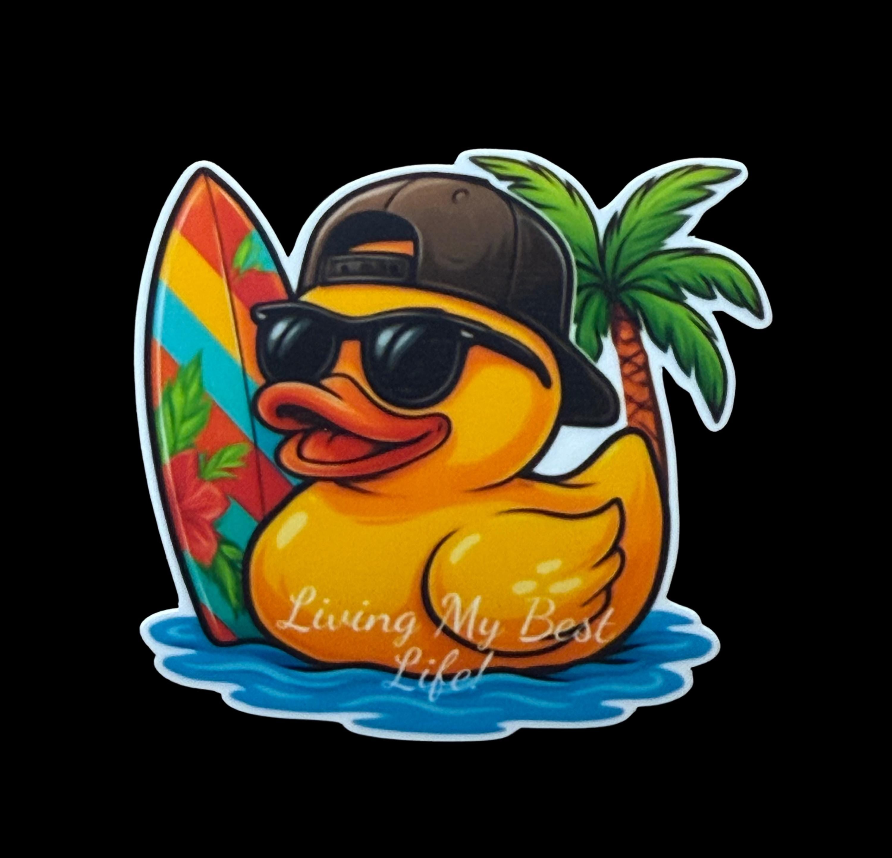 A cartoon rubber duck wearing sunglasses and a baseball cap, holding a surfboard, with a palm tree and the text &quot;Living My Best Life&quot; written on it.