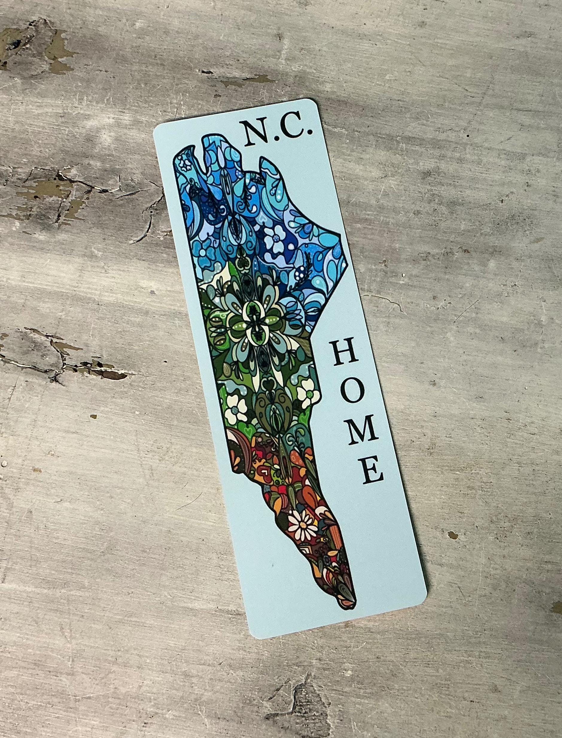 A colorful bookmark with a stylized map of North Carolina, featuring the state&#39;s name and the word &quot;HOME&quot; prominently displayed.