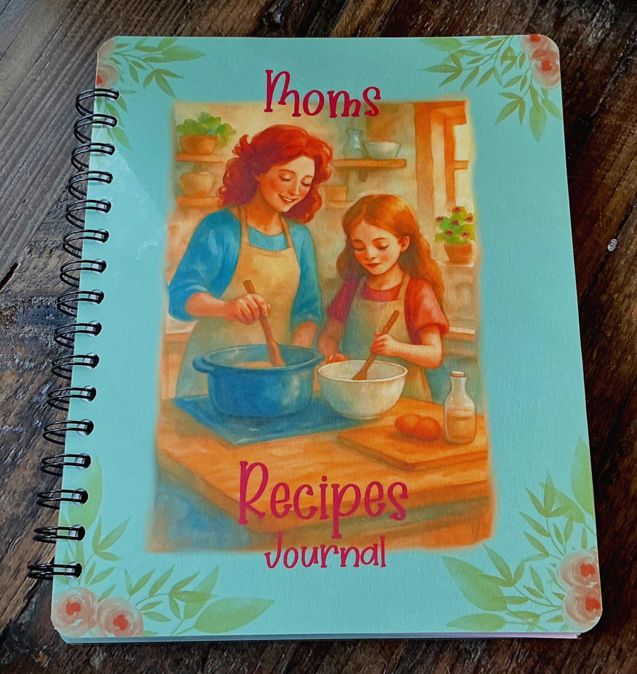 The image is a spiral-bound cookbook titled &quot;Moms Recipes Journal&quot; with illustrations of a mother and daughter cooking together in a kitchen.