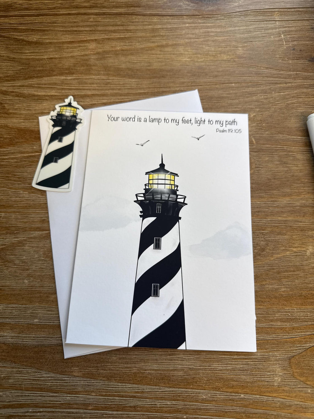 a lighthouse with a black and white striped pattern, and there is a small sticker of a lighthouse on the left side of the image.