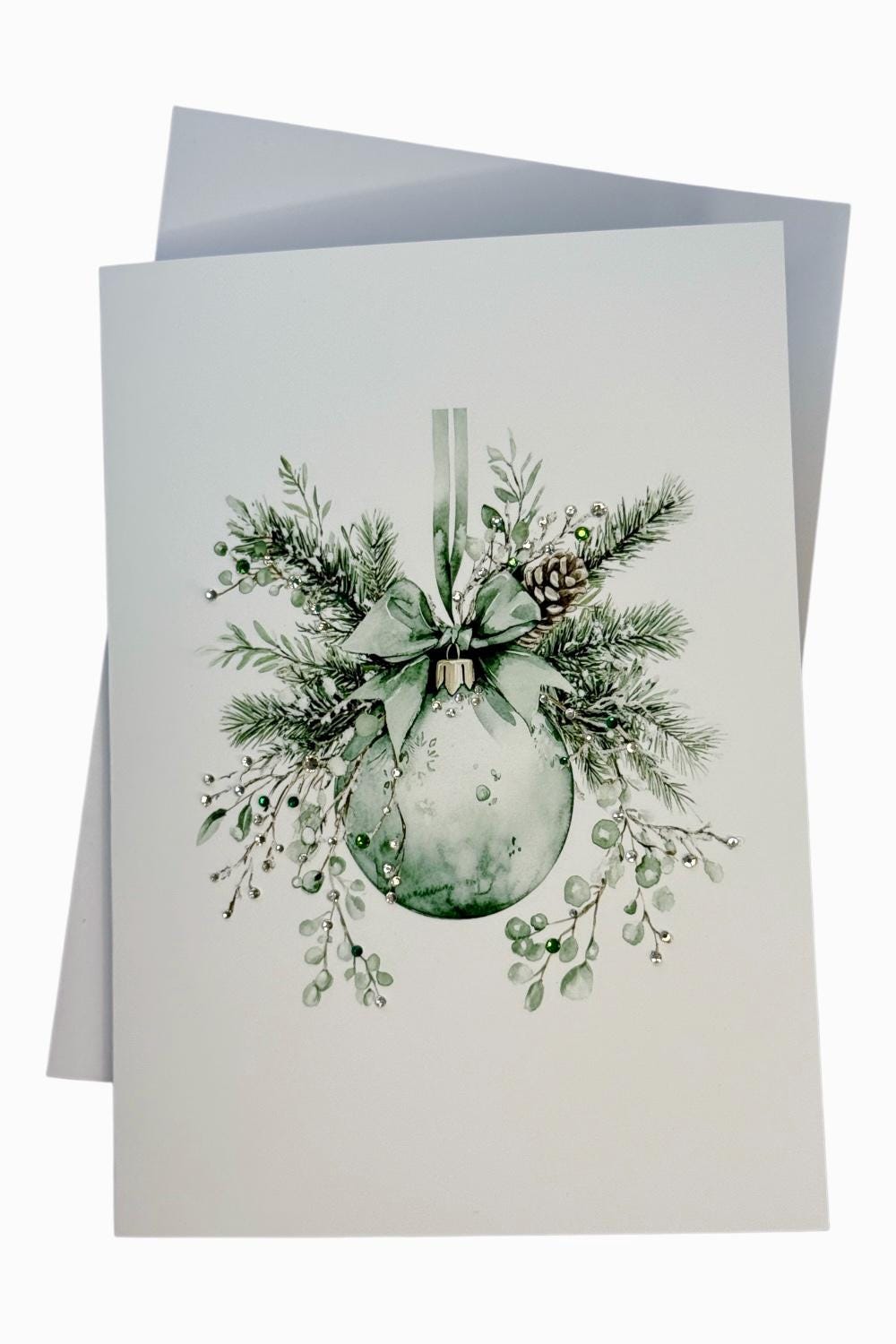 A watercolor painting of a Christmas ornament with greenery and berries, set against a white background.