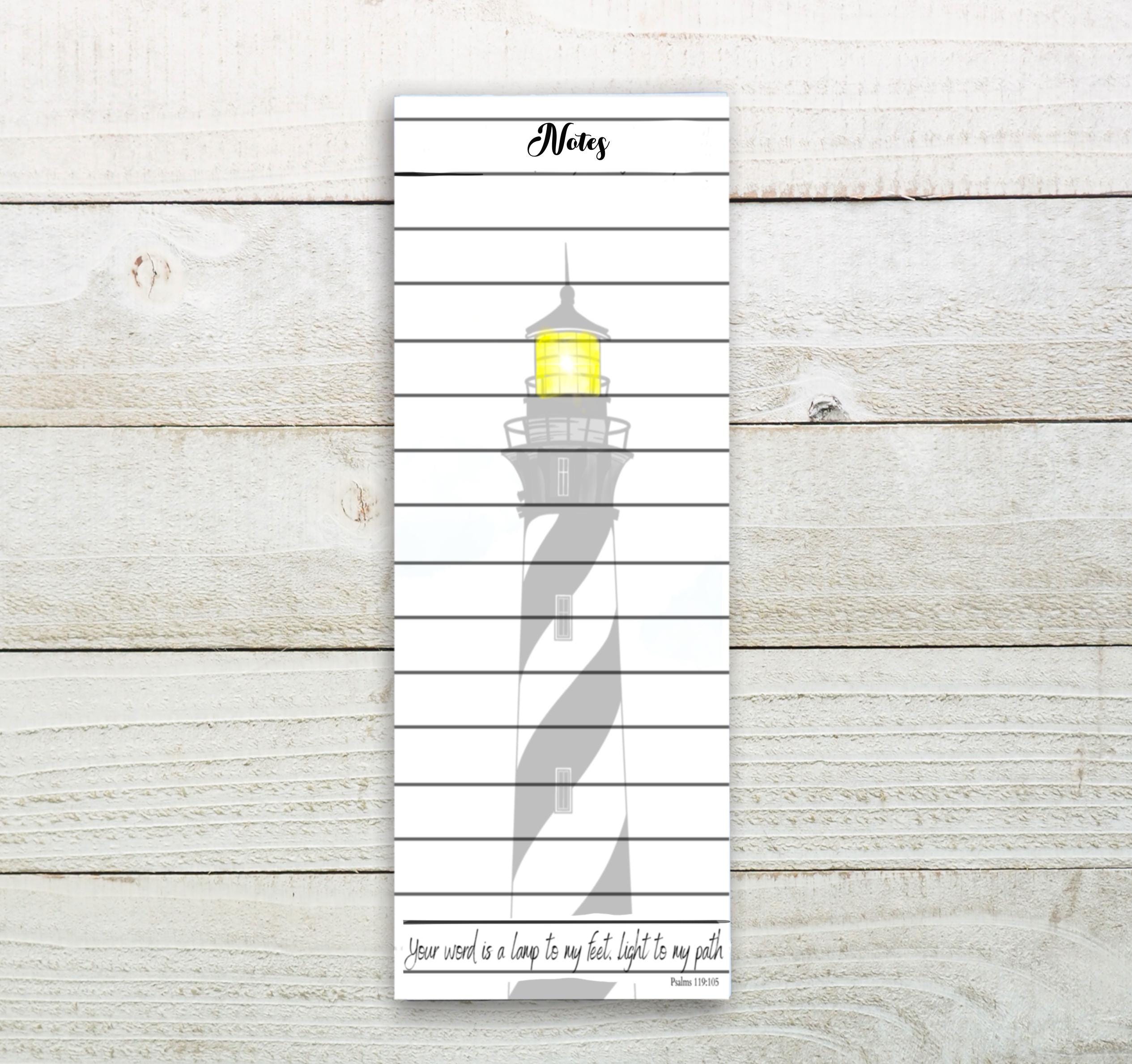 A white vertical notebook with a black and white lighthouse illustration on the cover.