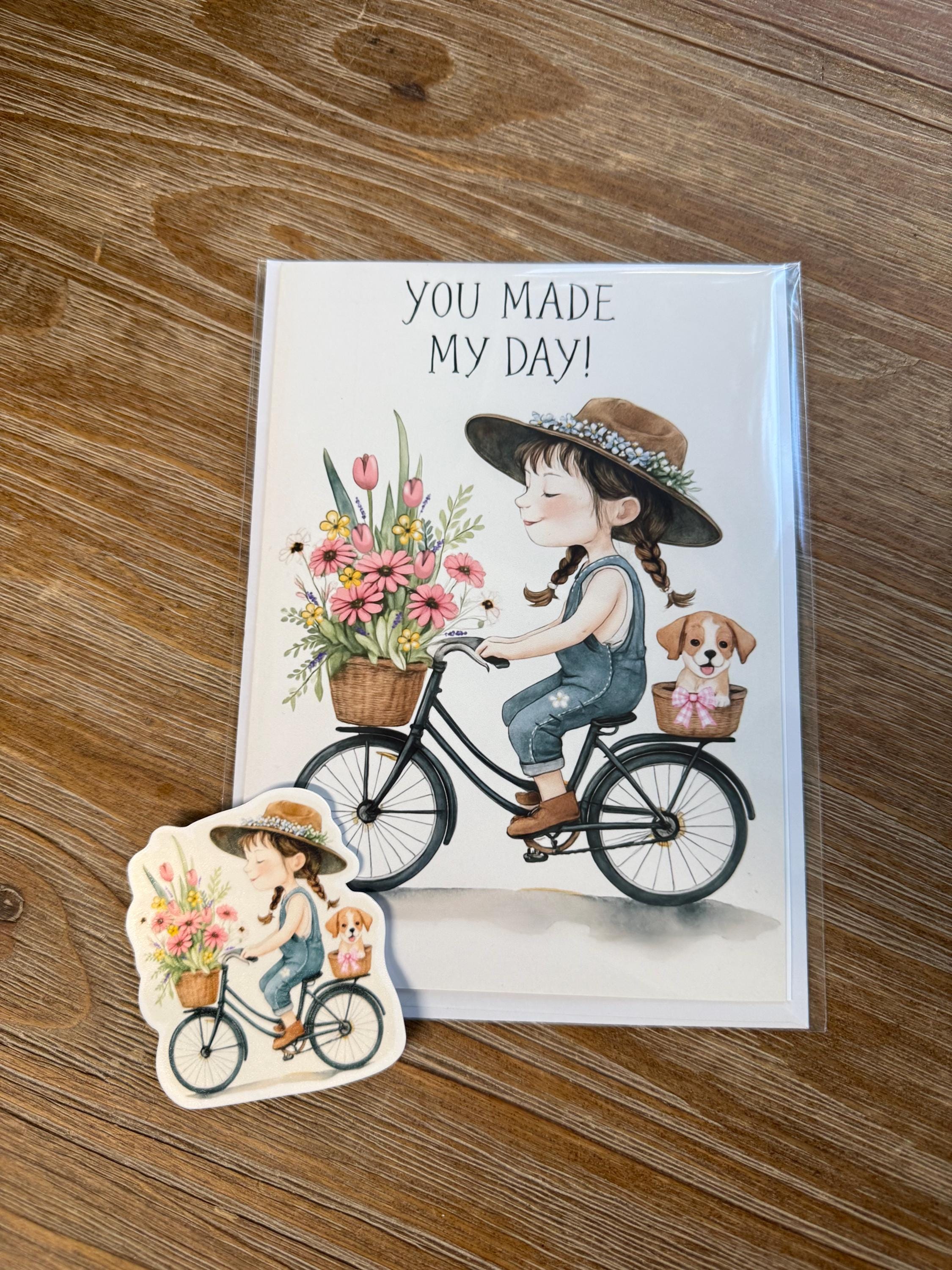 a greeting card with a girl riding a bicycle and a sticker depicting a girl riding a bicycle with flowers in a basket.