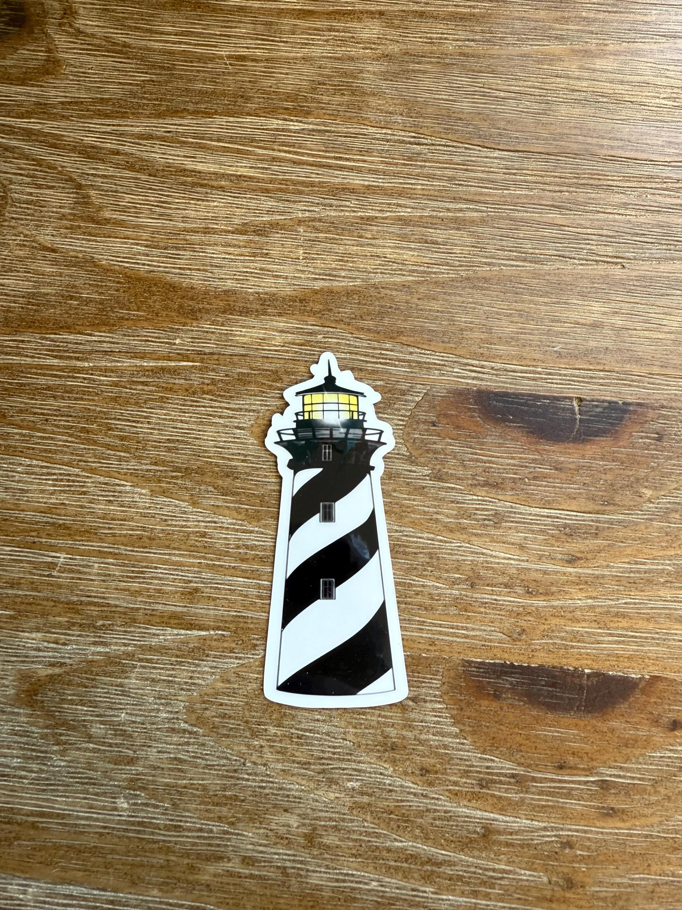 A sticker of a lighthouse is placed on a wooden surface.