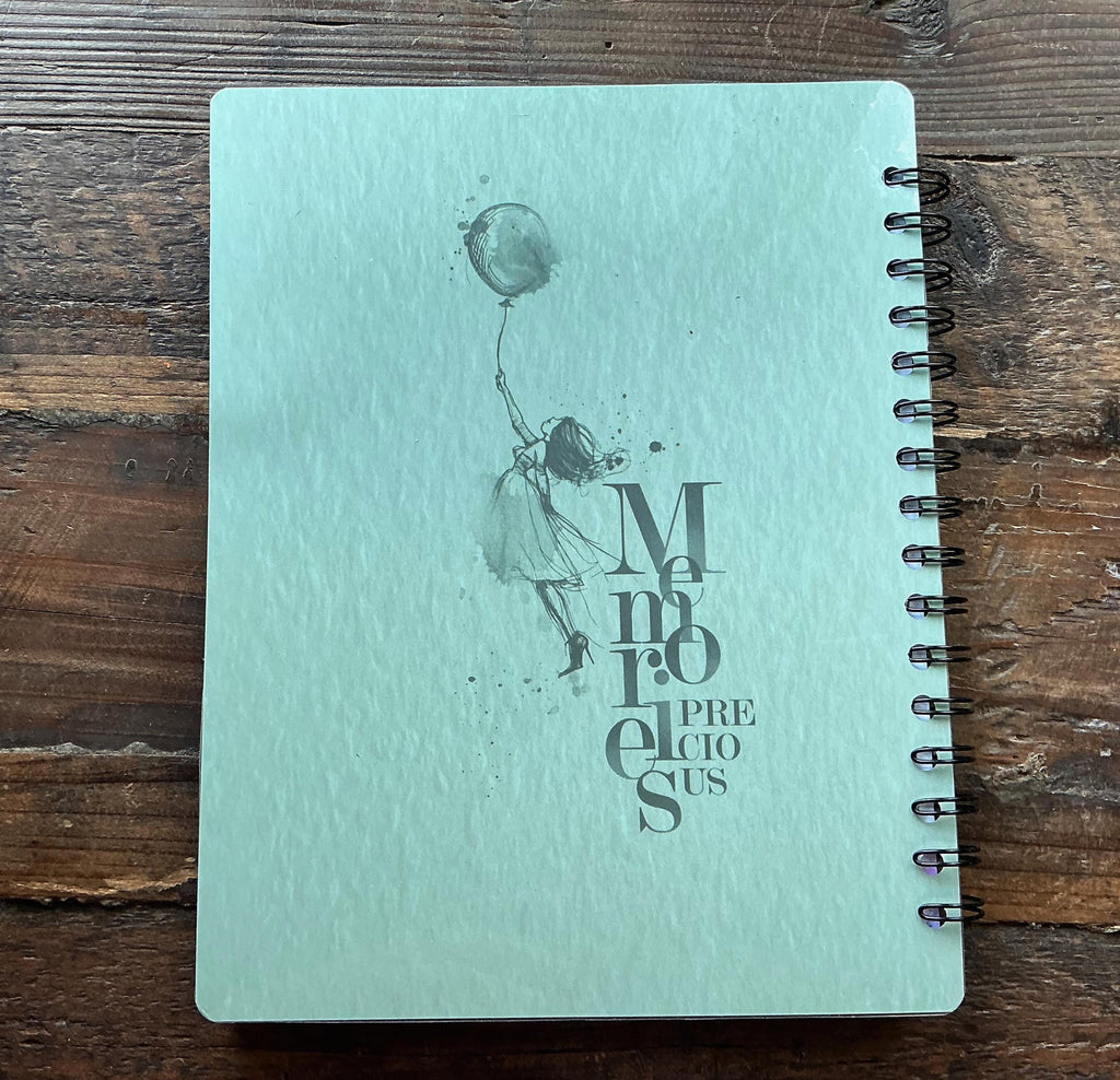 a light blue notebook with a black and white illustration of a person holding a balloon.
