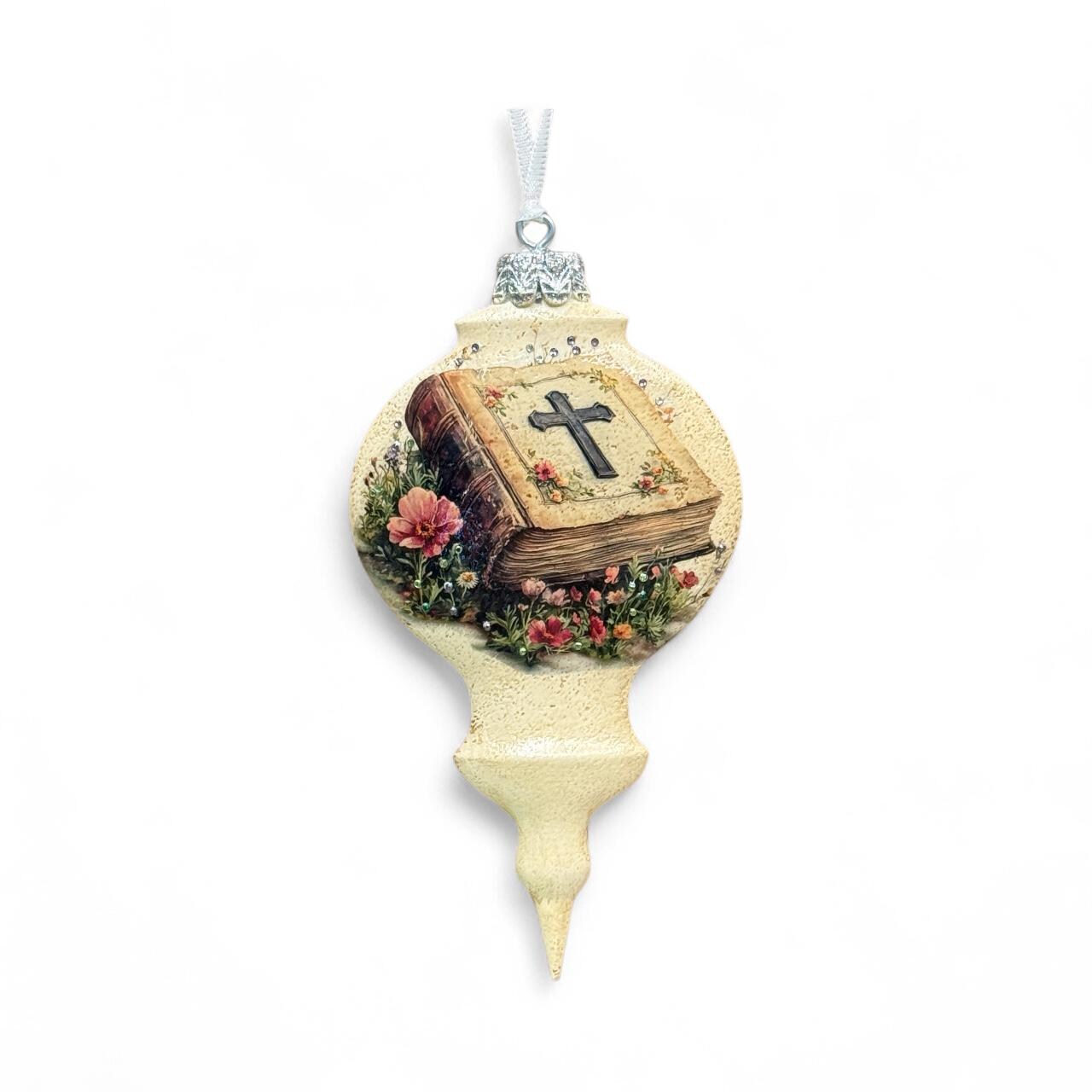 A decorative ornament with a cross on top, featuring a book and flowers.