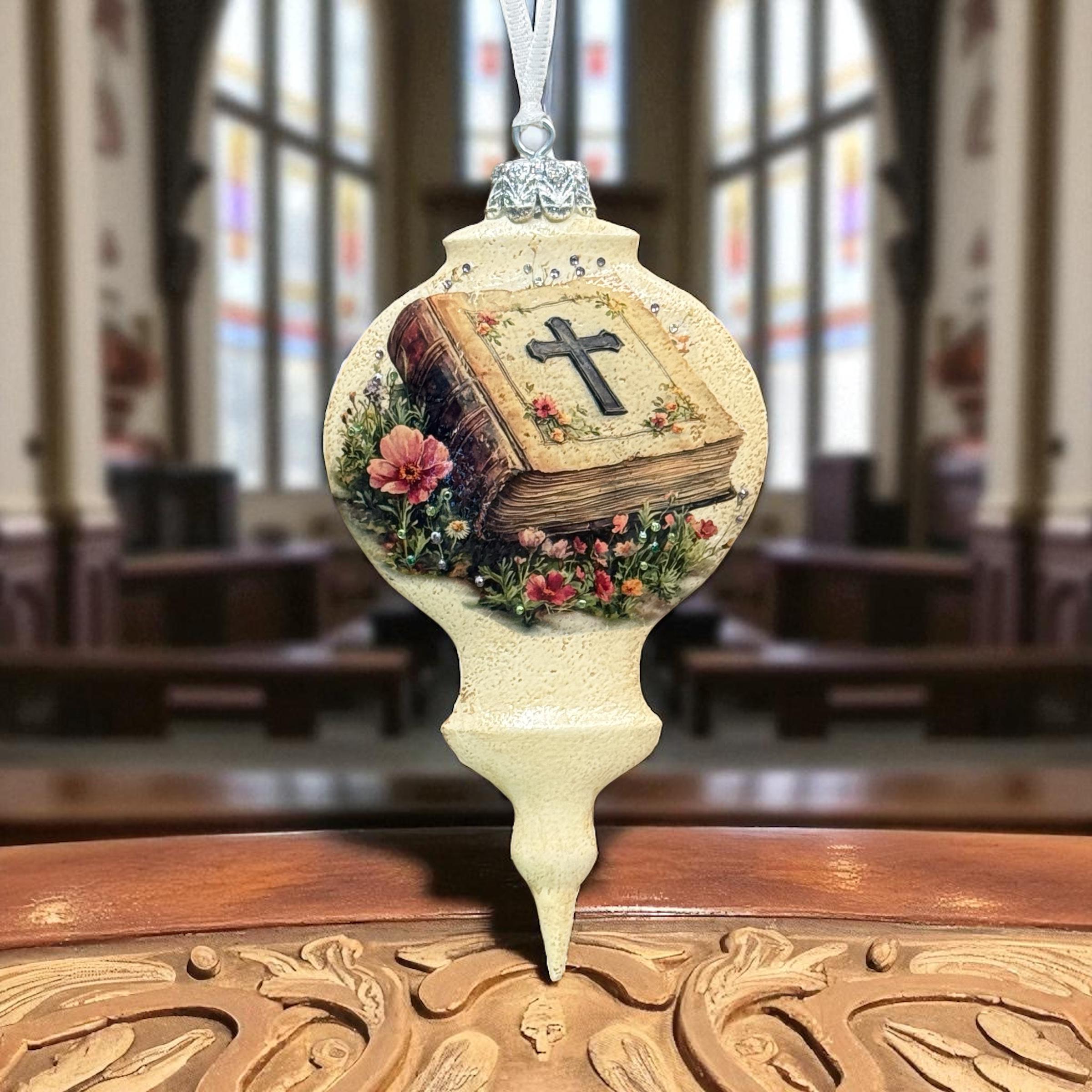 A decorative ornament featuring a cross on a book, placed on a wooden surface.