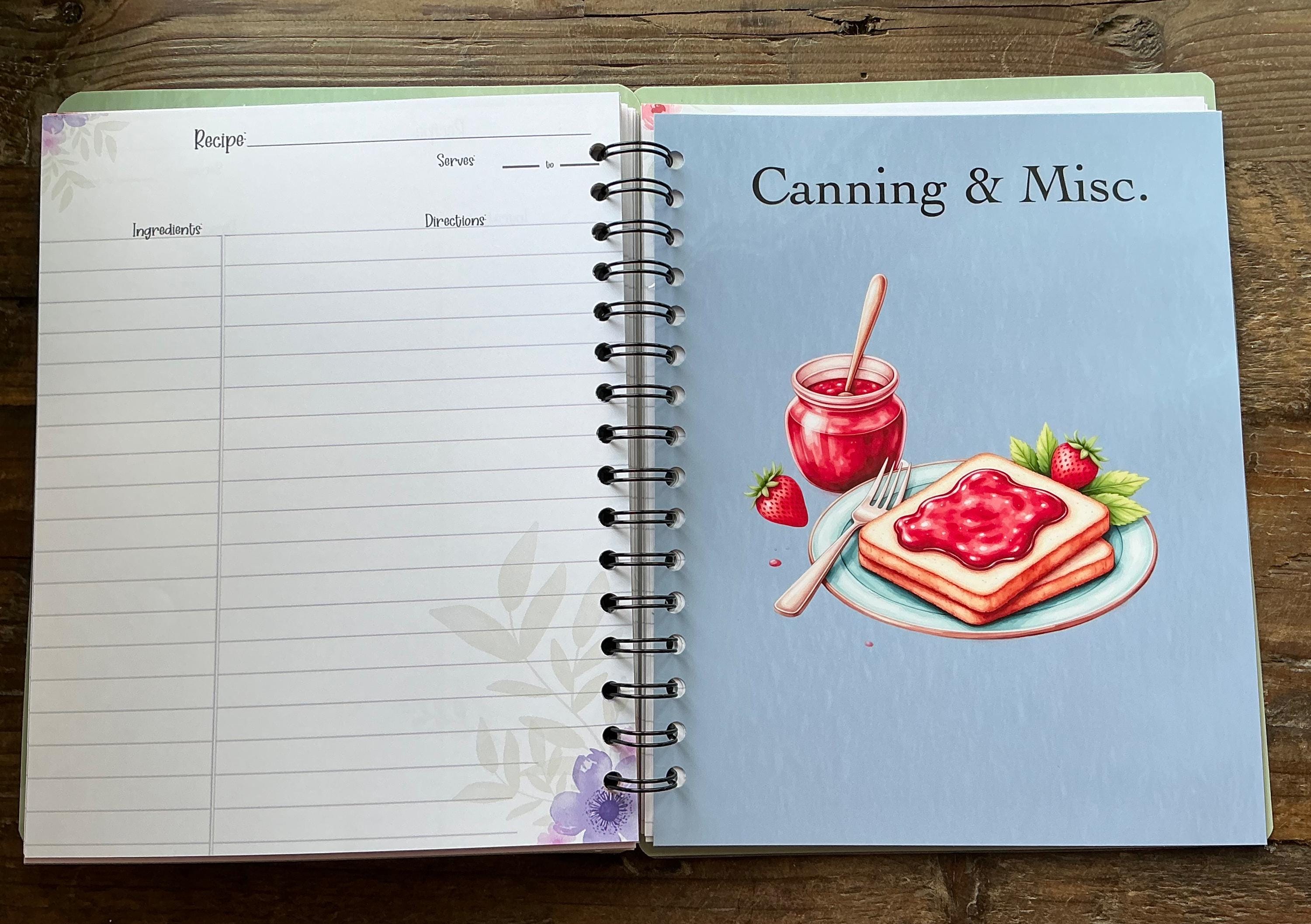 an open spiral-bound notebook with a recipe book cover on the right side, featuring an illustration of a jar of jam and a slice of toast with strawberry jam.