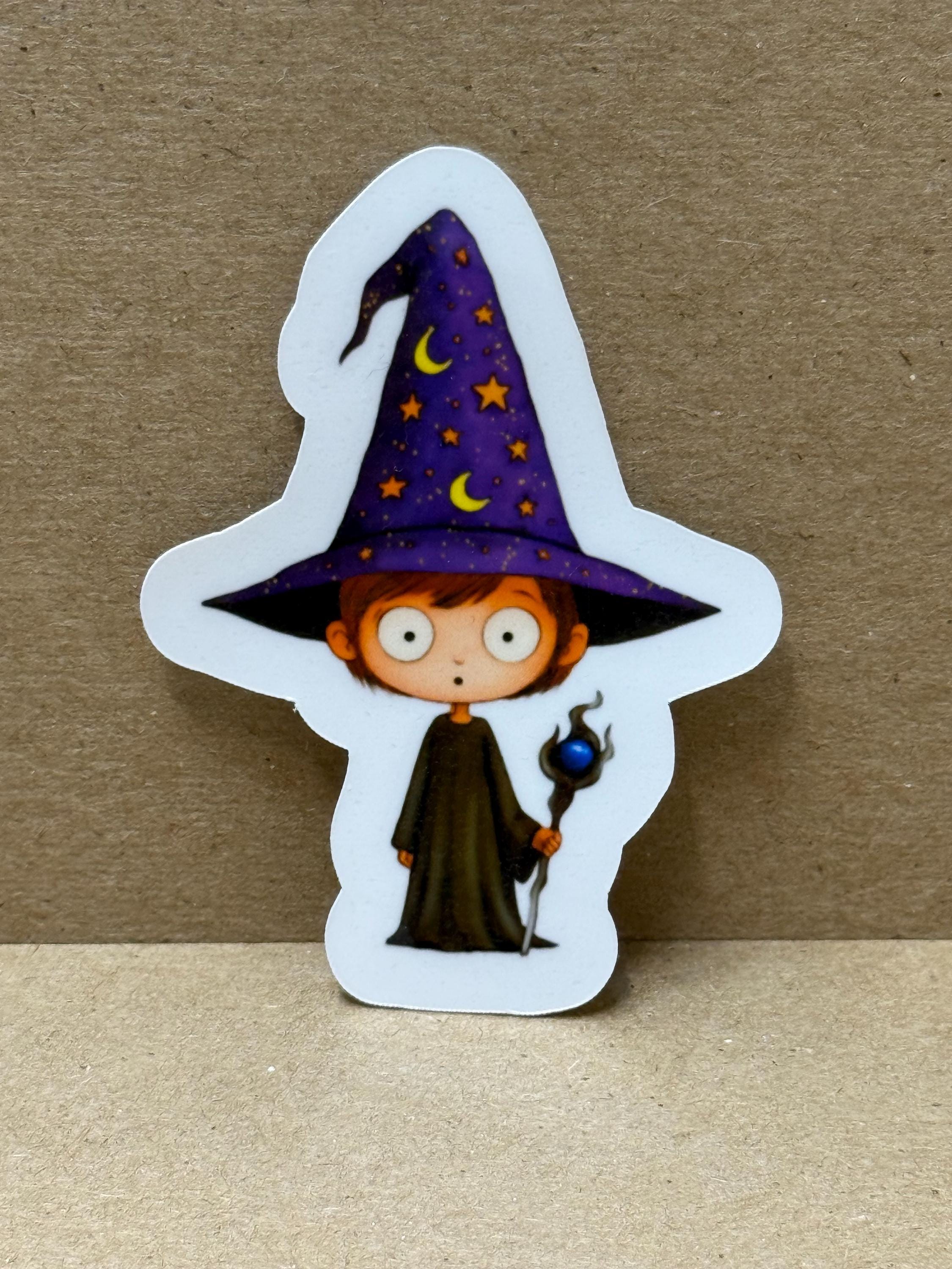 A sticker depicting a cartoon character wearing a purple wizard&#39;s hat with stars and crescent moons, holding a wand and a blue orb.
