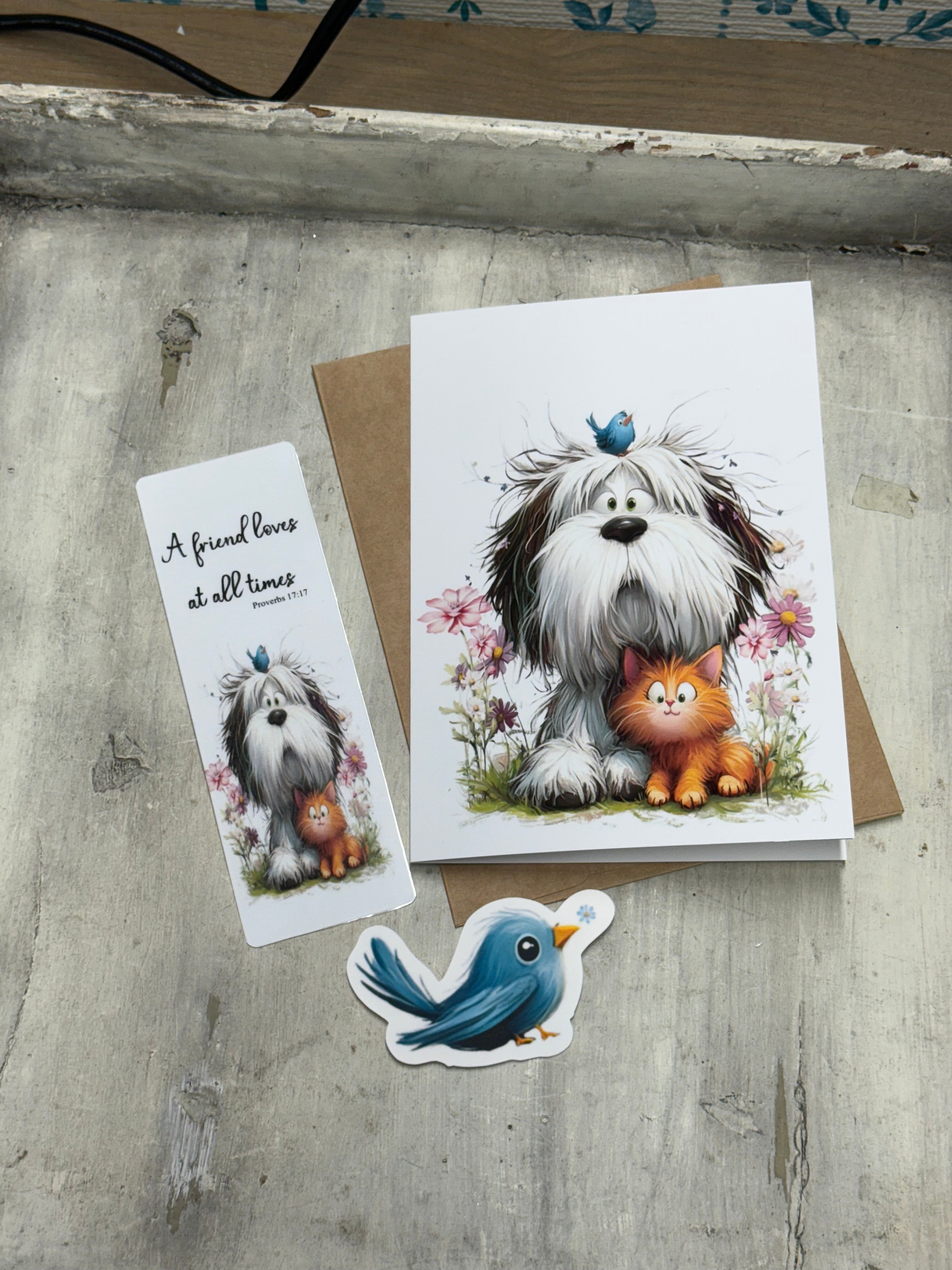 a greeting card with a dog and a cat, along with a small bird-shaped sticker, all placed on a wooden surface.