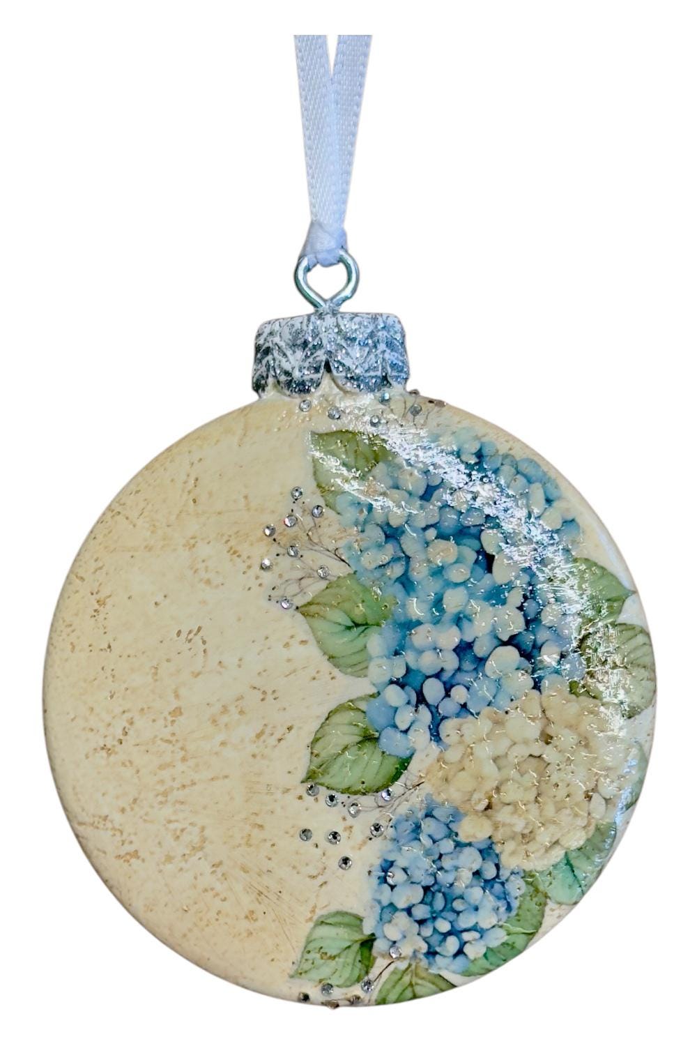 A decorative ornament with a floral design, featuring blue and white flowers and leaves.