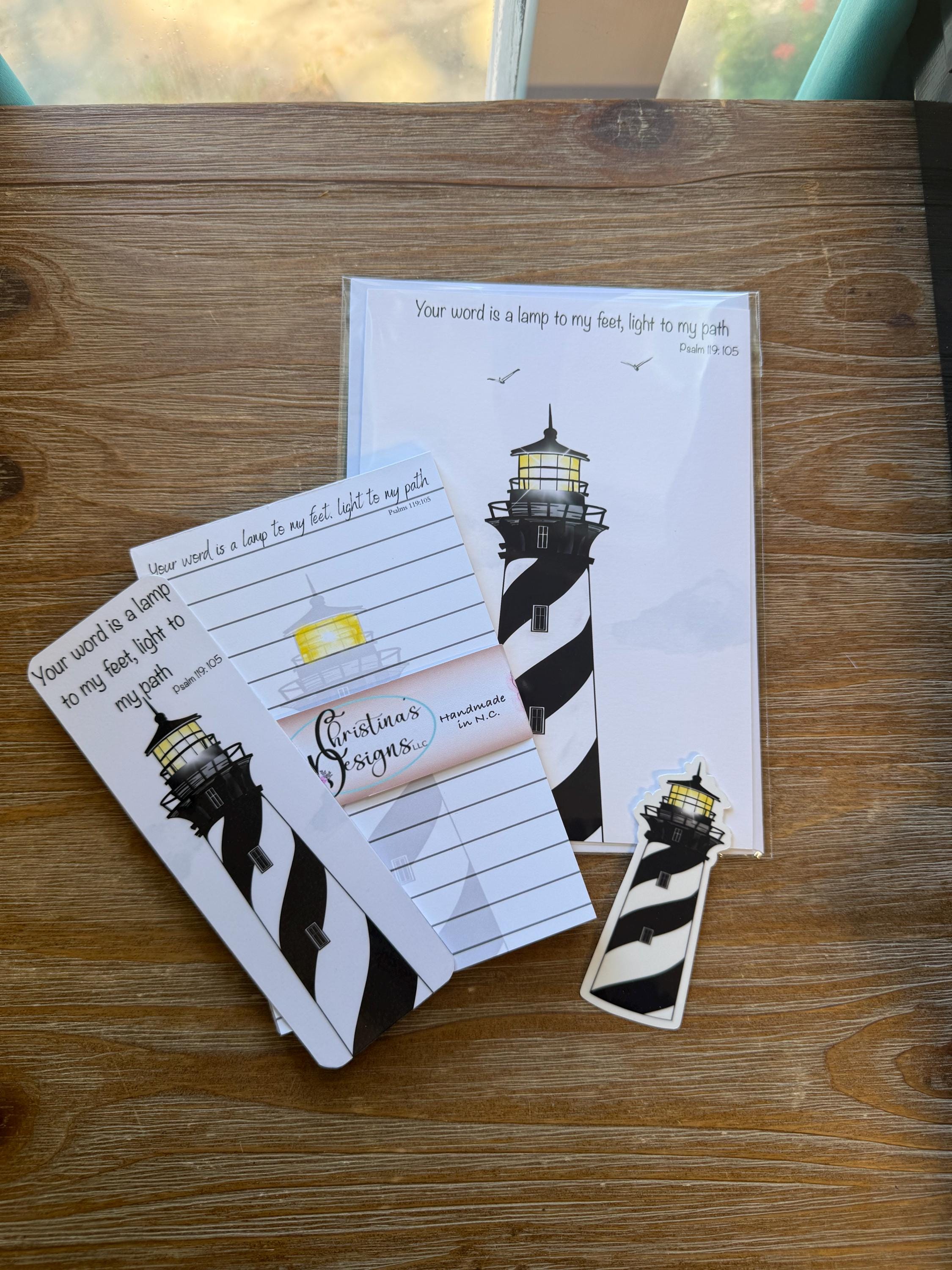 a wooden table with a few items on it, including a piece of paper with a lighthouse design, a small black and white striped object, and a set of lined paper notepads.