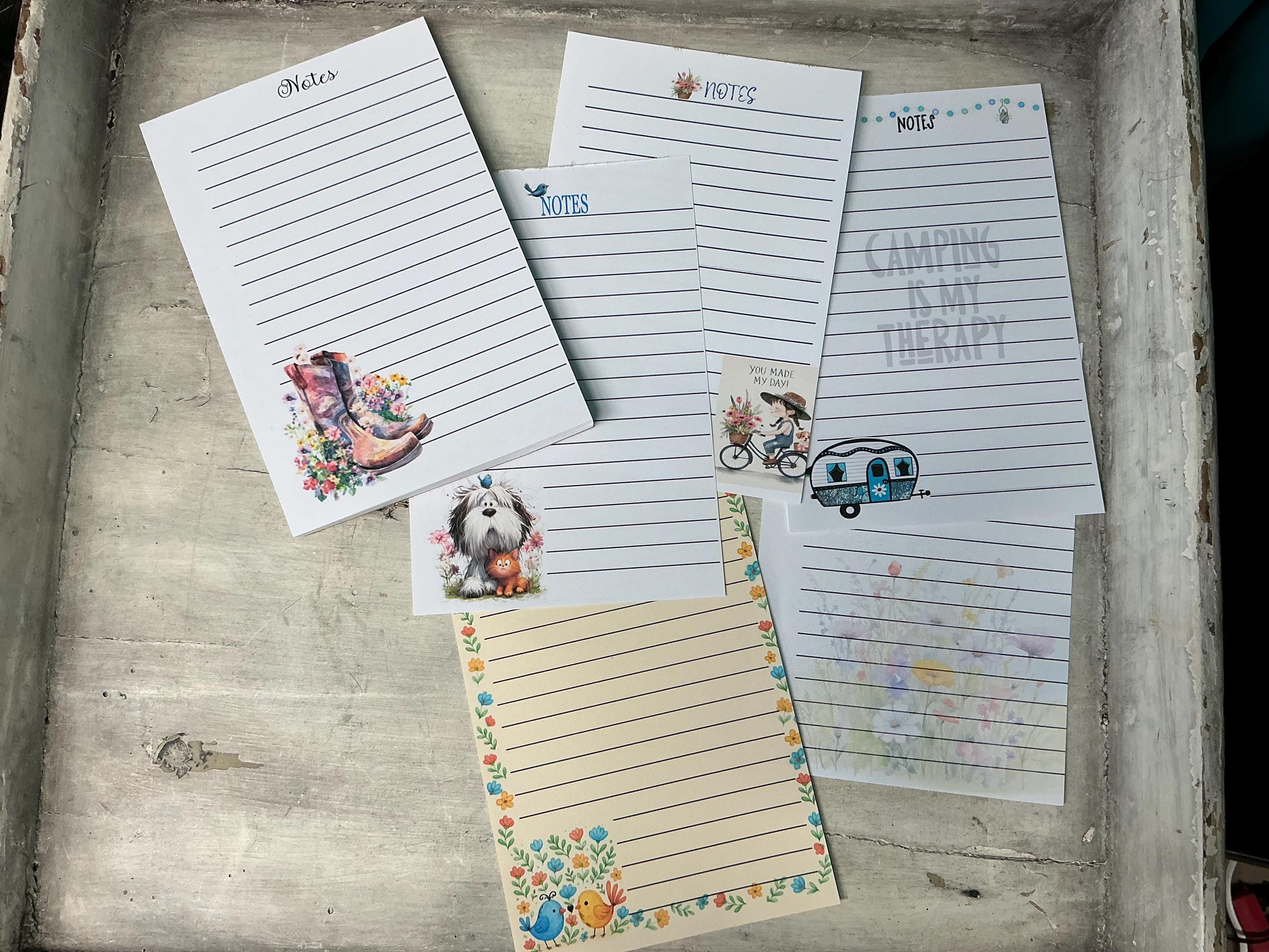 a collection of lined paper pads with various illustrations and text, including a dog, a bicycle, and camping-related imagery.