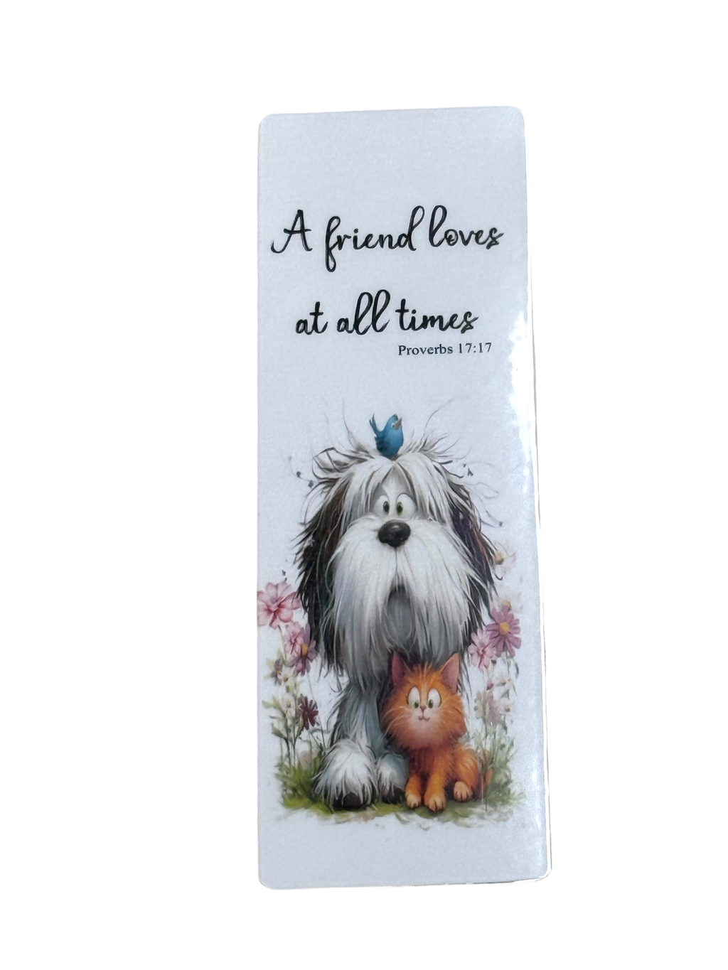 A white dog and a cat sitting together in a field with flowers, accompanied by a blue bird on its head.
