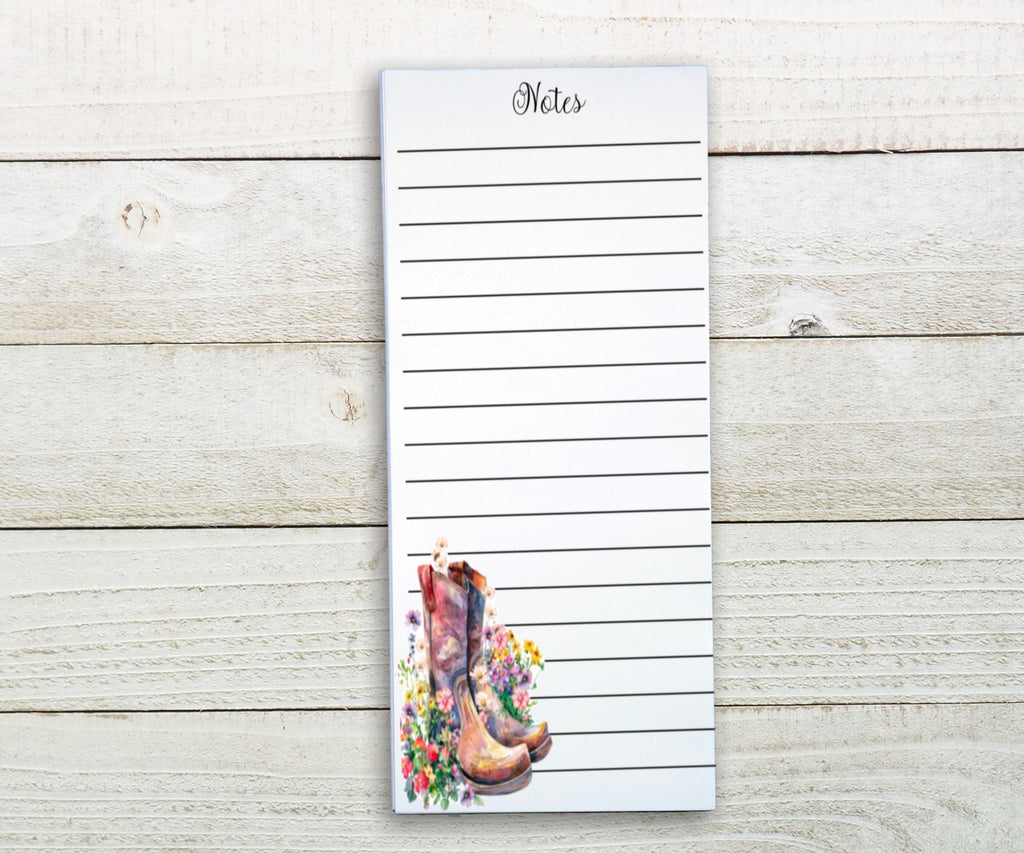 A lined notepad with a floral design on the cover, placed on a wooden surface.
