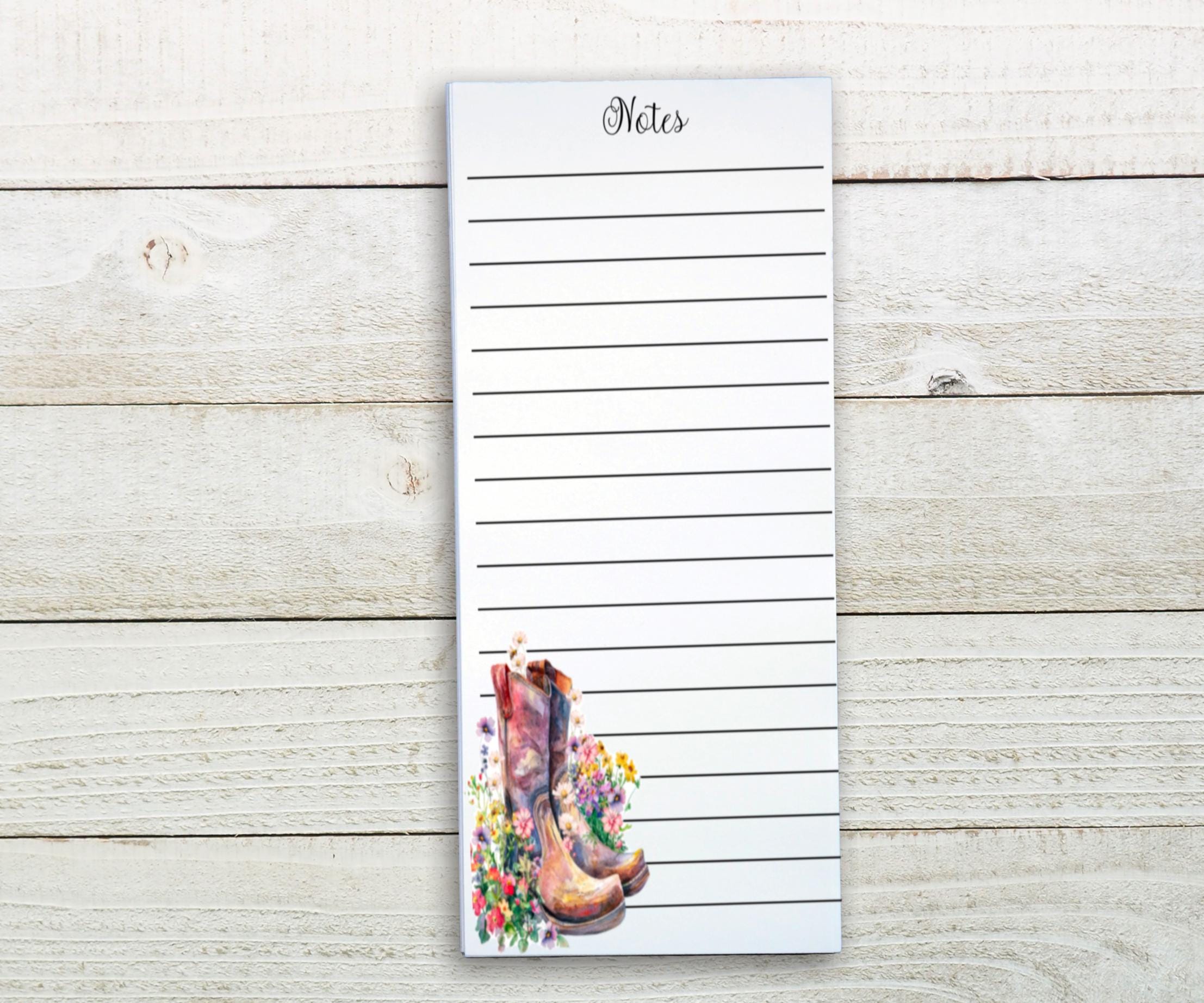 A lined notepad with a floral design on the cover, placed on a wooden surface.