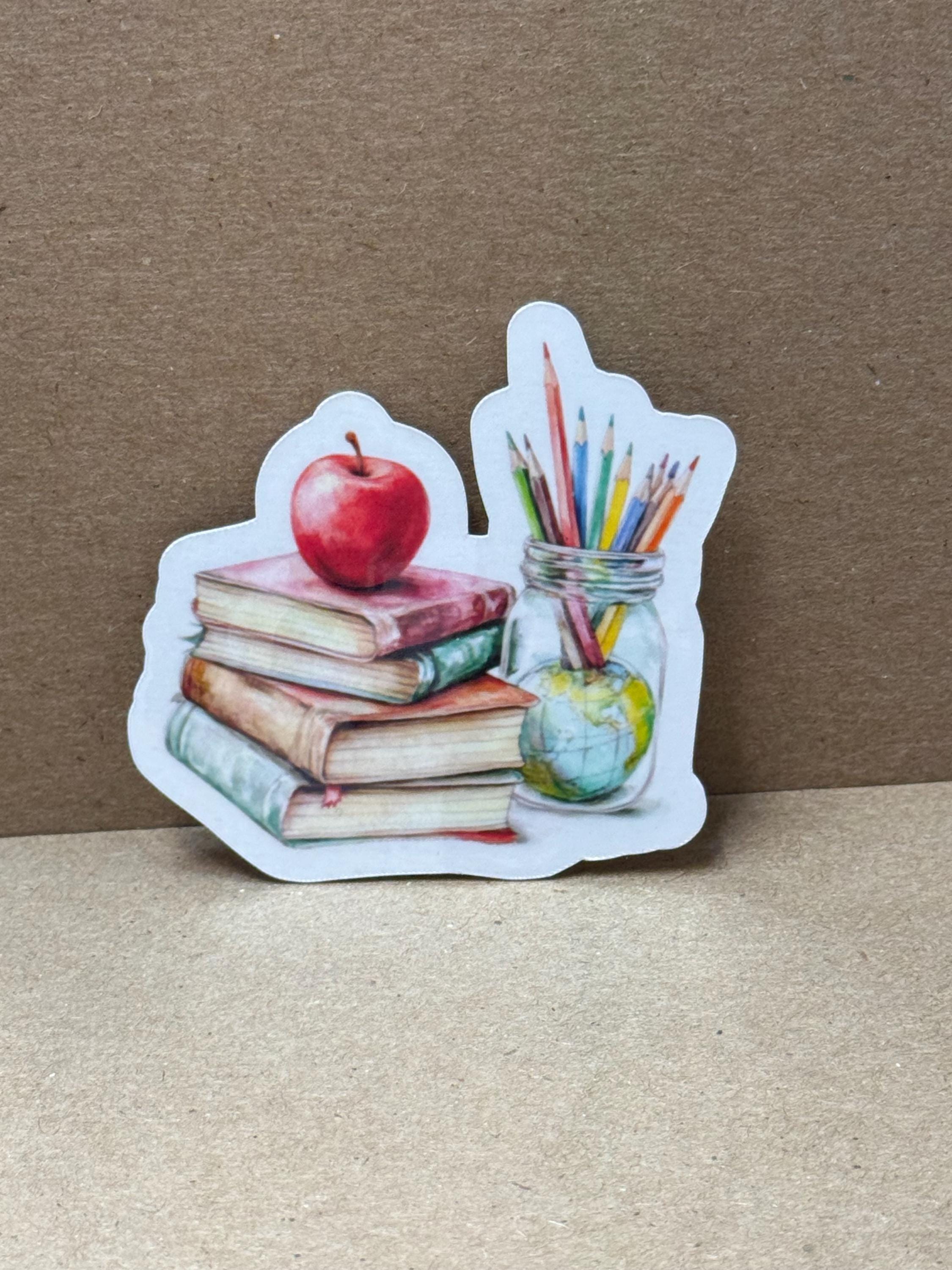 A sticker depicting a jar filled with colored pencils, an apple, and books, all arranged on a brown surface.