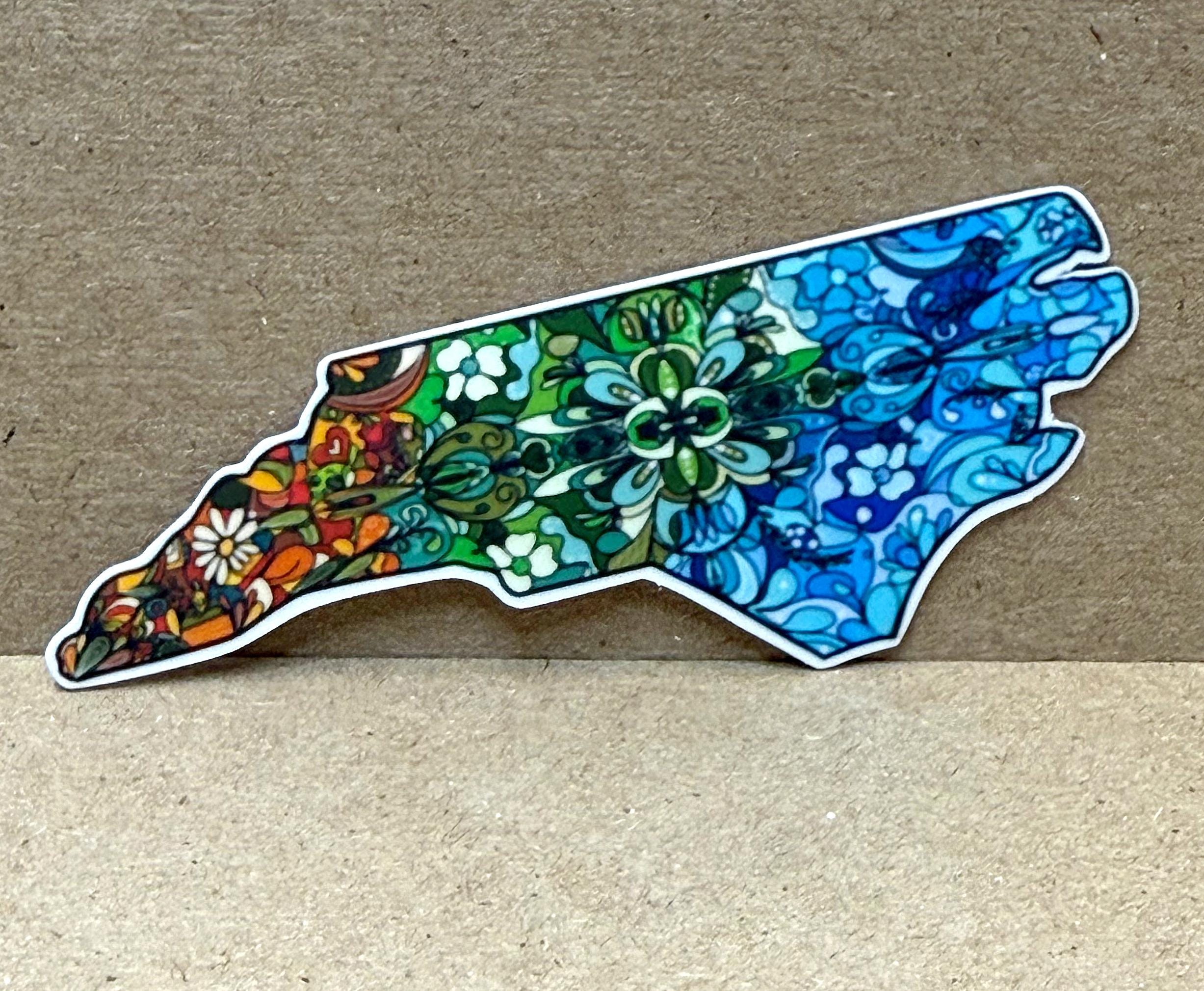 A colorful sticker depicting a stylized map of North Carolina with intricate floral and abstract designs in various colors.